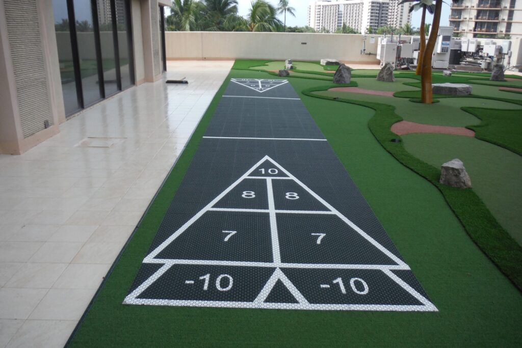 shuffleboard court alongside miniature golf course atop the roof of a hotel