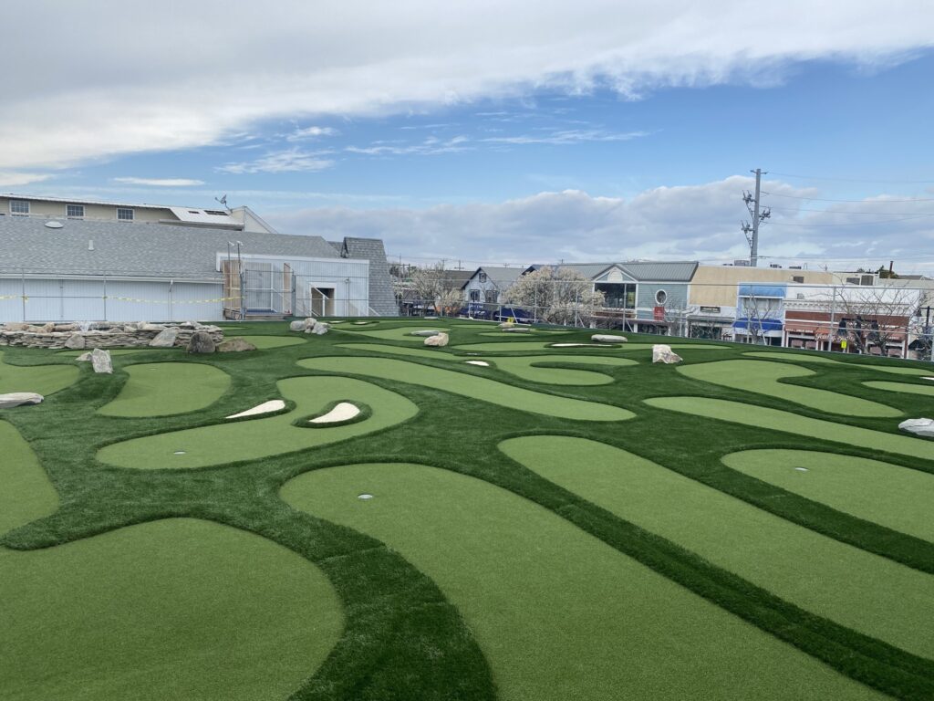 miniature golf course atop the roof of a design company - resembles a real golf course with rough & putting turf
