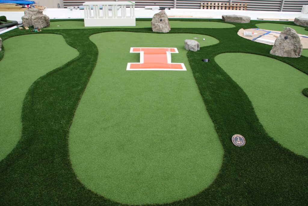 Miniature golf course atop the roof of an athletic facility at a college - football themed props throughout
