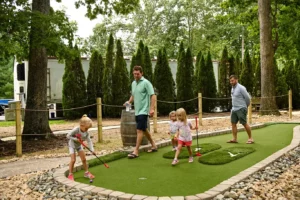 Young girl begins to set up her next putt on hole #1 as her Dad and friends walk toward her