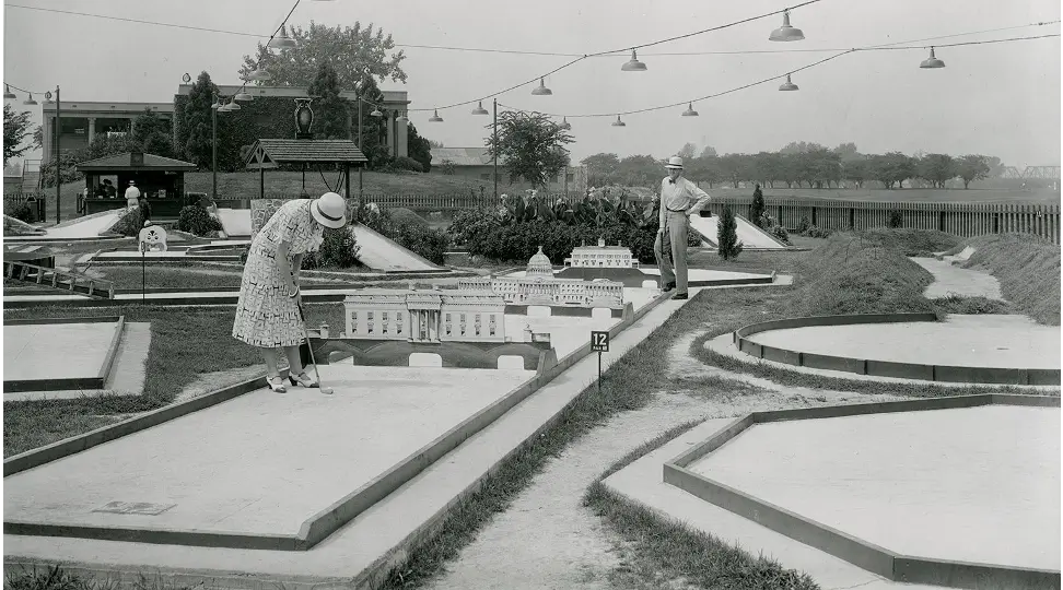 Players on 1930s course with landmark DC obstacles and Wishing Well with rooftop and owl