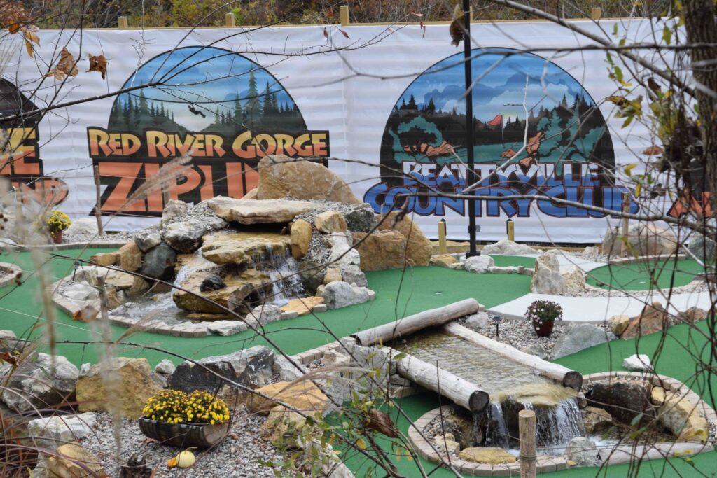 miniature golf course with rocks, water elements, and wooden bridges