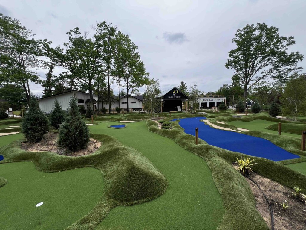 Mini Golf course with natural landscaping surround the course, including a bright blue hole that resembles Lake Michigan