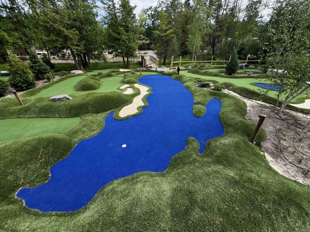 Mini Golf course with natural landscaping surround the course, close up on a bright blue hole that resembles Lake Michigan