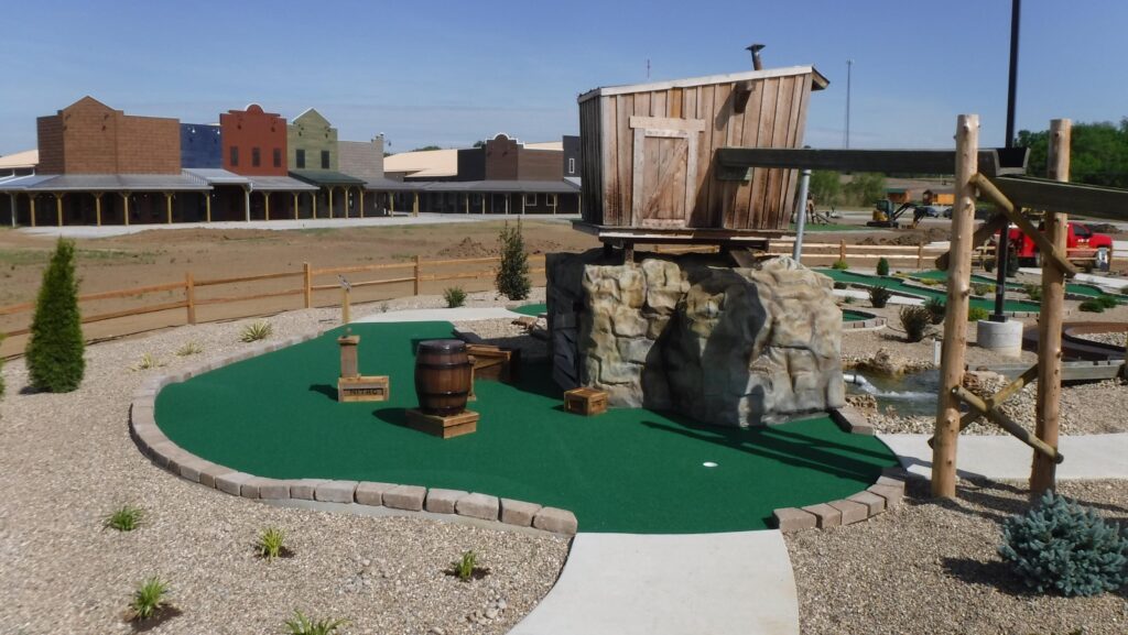 miniature golf course with wooden barrels as props, rock & wooden structures that make up the western theme of this course