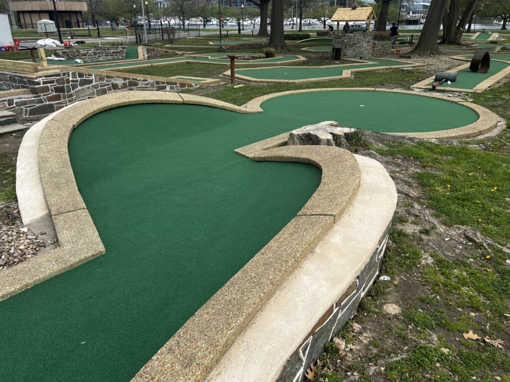 miniature golf course in Washington DC, golf holes with green turf bordered in tan cement 