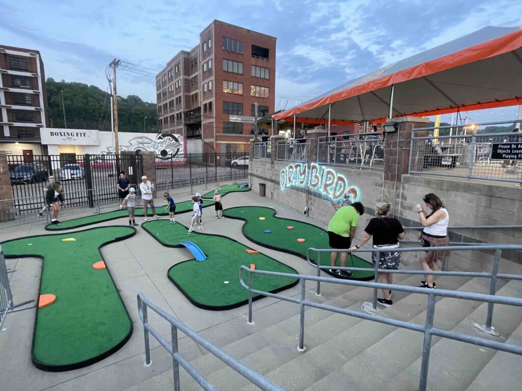 miniature golf course outside at a minor league baseball stadium, portable course with colorful faux wood shapes and metal blue bridges