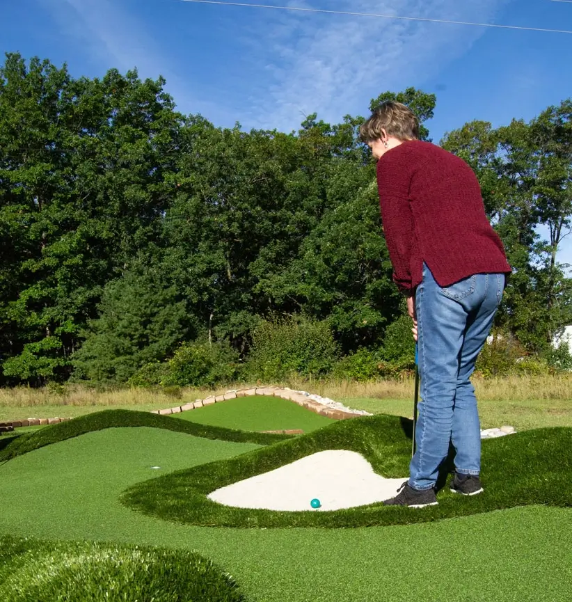 Player watches her putt along a natural-looking AGS Bunkers & Bumps™ miniaturized golf fairway